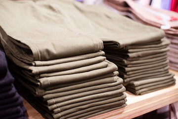 Stacks of various trousers on shelves in a clothing store