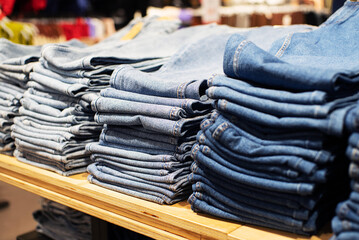 Stacks of various blue jeans on shelves in a clothing store