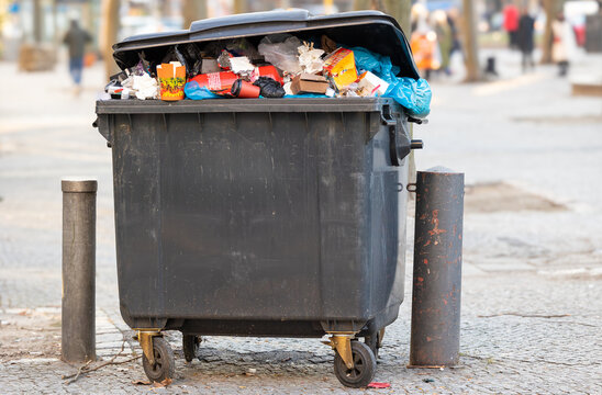 &Uuml;berquellender M&uuml;llcontainer, der auf der Stra&szlig;e steht und auf seine Abholung durch die M&uuml;llabfuhr wartet