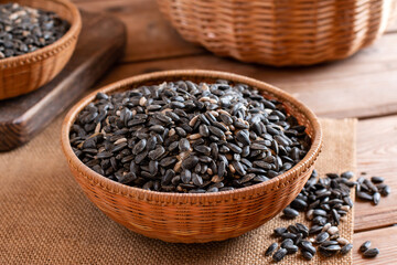 Pile of black sunflower seeds on wooden elm slab, selective focus