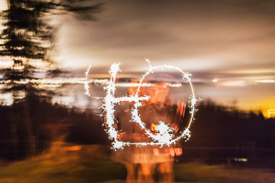 Woman drawing the number 40 with sparkler at night