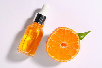 Aromatic tangerine essential oil in bottle and citrus fruit on white table, top view