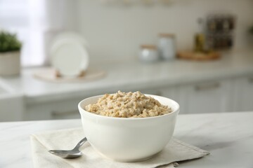 Breakfast time. Tasty oatmeal in bowl on white marble table