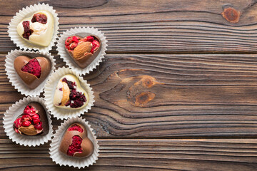 chocolate sweets in the form of a heart with fruits and nuts on a colored background. top view with space for text, holiday concept