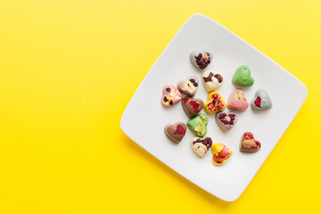 Plate with different chocolate on colored background. Assortment of fine chocolates top view vith copy space Health and obesity concept