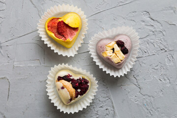 chocolate sweets in the form of a heart with fruits and nuts on a colored background. top view with space for text, holiday concept