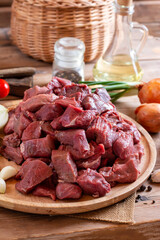 Raw fresh beef or lamb cubes. Diced red beef meat on a wood serving board. Raw casserole or stewing beef diced. Goulash.