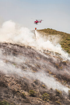 Helicopter dropping flame retardant, ammonia sulfate, onto wild fire in the mountains of Corsica.