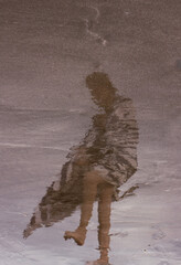 the blurred silhouette of a girl in the reflection on a wet beach