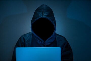 Male hacker in dark room using laptop internet hacking - obrazy, fototapety, plakaty
