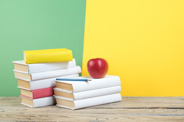 Fototapeta premium Books stacking. Books on wooden table and green, yellow background. Back to school. Copy space for ad text.