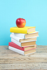 Books stacking. Books on wooden table and blue background. Back to school. Copy space for ad text.