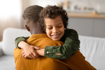 Black boy hugging father with content smile