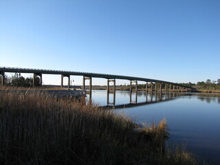 Vast bridge extends over a serene river, surrounded by lush vegetation