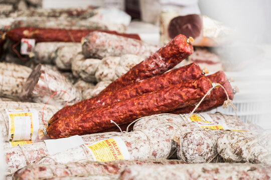 Salami sticks stacked at a market stand. Salo, Italy