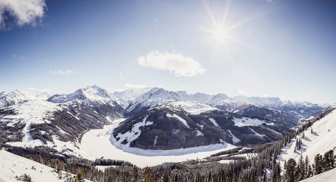 Mountain landscape in winter with sun in background. Zillertal, Austria