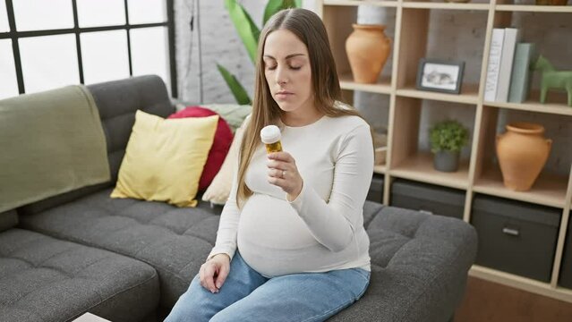 A pregnant hispanic woman examines medication in a modern living room, portraying healthcare during maternity.