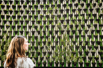 Woman standing in front of green wall of plants. Llubijana, Slovenia