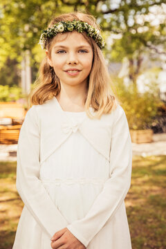 Young girl wearing a white spring dress and a flower wreath in her hair. Munich, Germany