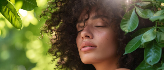 A young woman with curly hair gently closes her eyes, embraced by the lush greenery, in serene harmony with nature