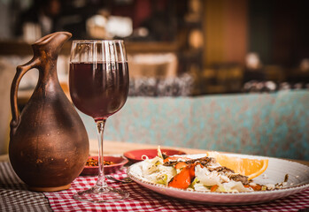 Greek salad and glass of red wine on the oak table