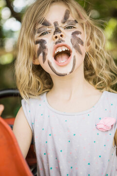 Young girl with painted face growling into the camera during carnival season. Munich, Germany