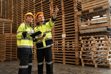 Fototapeta premium Caucasian businessman and woman checking pallets wood stock with bar code scanner and tablet computer at pallets warehouse 