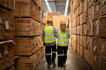 Back Caucasian team businessman and woman use notebook computer working with stock timber background at wood factory	