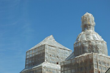 A building sheathed on the outside with transparent polyethylene film and wooden slats. Street...