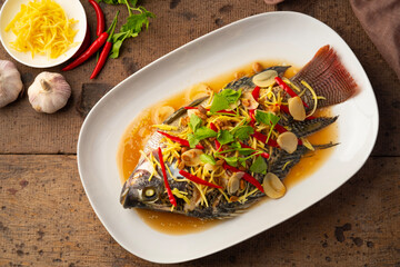 Steamed Tilapia fish with Soybean Paste sauce in white plate.Top view