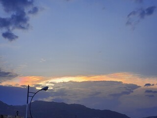 A stunning sunset view of a sky filled with attractive colors that capture the eye behind the clouds and mountains