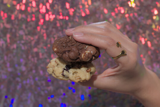 Hand holding two chocolate and walnut cookies