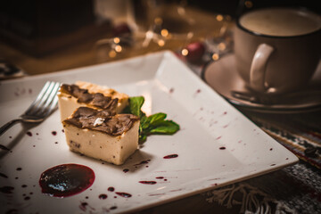 Cheesecake slice, New York style classical cheese cake on wooden background. Slice of tasty cake on white plate served with dessert fork