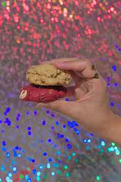 Hand holding a pair of walnut and red velvet cookies
