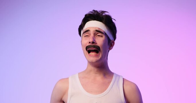 Portrait of a sad 80-90s mustachioed nerdy Caucasian man in grief, amused crying and shouting, while standing over purple background.