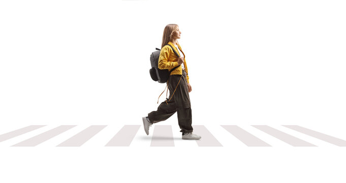 Female teenage student with a backpack walking over a pedestrian crossing