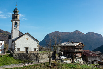 Fototapeta na wymiar Scenic view of remote alpine village of Sauris di Sotto in Carnic Alps, Friuli Venezia Giulia, Italy. Serene tranquil atmosphere in Italian Alps. Traditional wooden houses and church of Saint Oswald