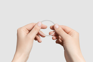 female hands holding hormonal contraceptive ring isolated on grey background - obrazy, fototapety, plakaty