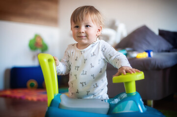 Cute happy baby boy playing with his colorful big toy truck in the living room. Joy and happiness concept. Love and family emotion