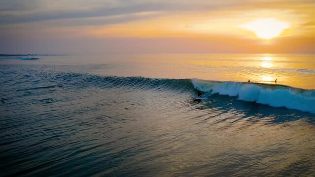 Surfer catching a wave under a stuning sunset