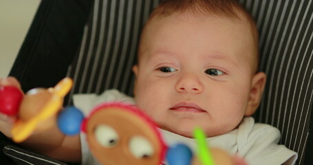 Obraz premium Baby newborn in chair seated with spinning toy in the foreground