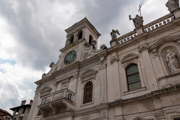 Scenic view of catholic church of San Giacomo on Piazza Matteotti, Udine, Friuli Venezia Giulia, Italy, Europe. Historic bell tower and row of religious statues on the roof. Urban tourism. Cloudy sky