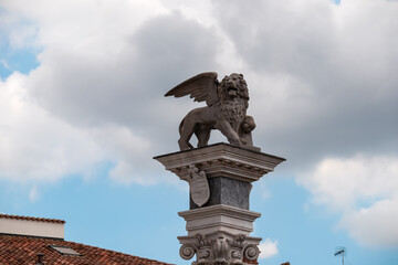 Statue of San Marco lion on the top of column outside the 16th century Renaissance Loggia di San Giovanni in Udine, Friuli Venezia Giulia in Italy. Landmark on town main square Piazza della Liberta