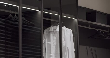 Black wardrobe with classic shirt , Luxury Bedroom With Walk In Closet. dressing room with things. Elegant Wooden Built Walk In Closet Decoration. Luxury Dressing Room With Closet.