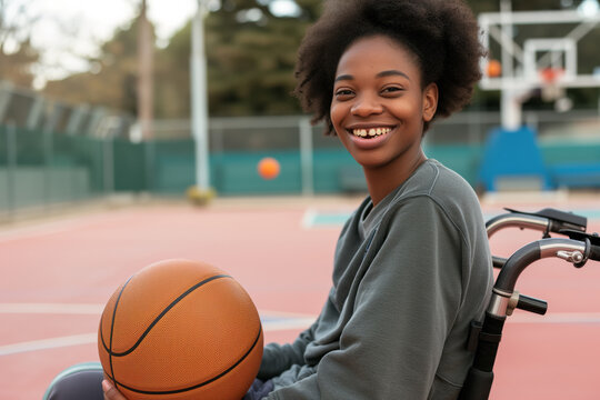 A disabled girl in a wheelchair holds a basketball on a basketball court and smiles, sports for the disabled