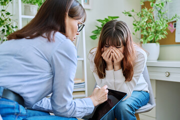 Sad, crying teenage girl at session in office of mental professional