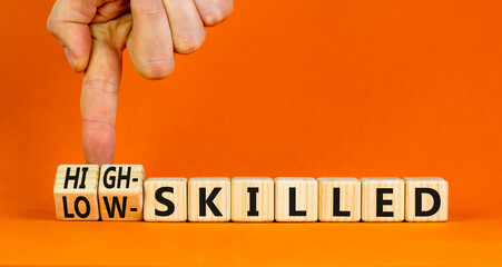 High or low skilled symbol. Concept words High-skilled or Low-skilled on beautiful wooden blocks. Beautiful orange background. Businessman hand. Business high or low skilled concept. Copy space.