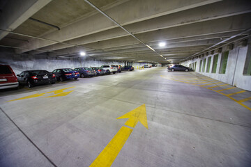 Bright Yellow Arrows in Parking Garage with Fluorescent Lights - Ground View