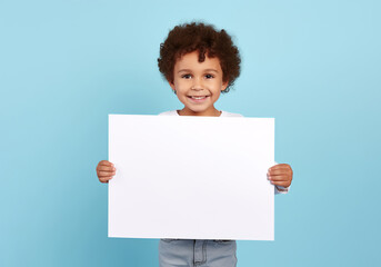 kid holding a blank placard sign poster paper in hands. empty space for editing on pastel blue background