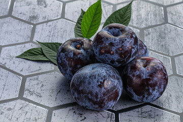 Raw purple plums heap with leaves
